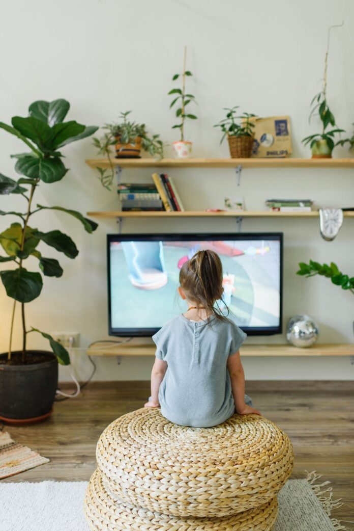pexels-photo-4740522 faceless girl watching tv on wicker stool at home